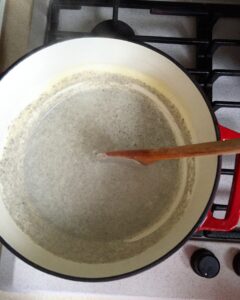 Finished creamy truffle sauce simmering in a pot with a wooden spoon resting in it