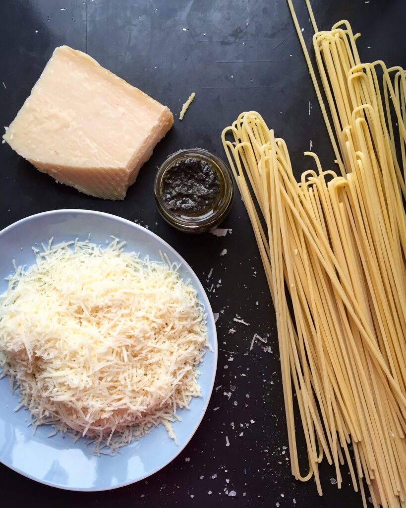 Parmesan wedge, truffle paste, freshly grated parmesan, and dry spaghetti arranged on a dark table