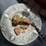 Oven-baked beef patty cut open on a decorative plate with a fork, showing the cooked ground beef inside