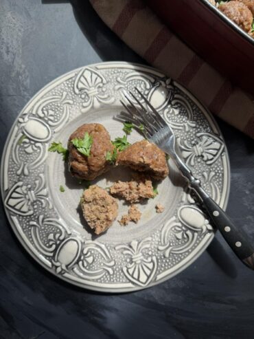 Oven-baked beef patty cut open on a decorative plate with a fork, showing the cooked ground beef inside
