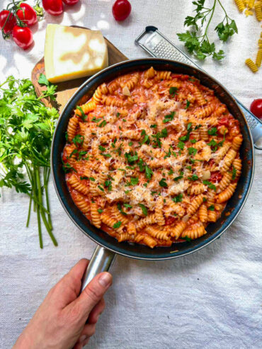 Overhead view of creamy tomato fusilli in a skillet topped with Parmesan and parsley.