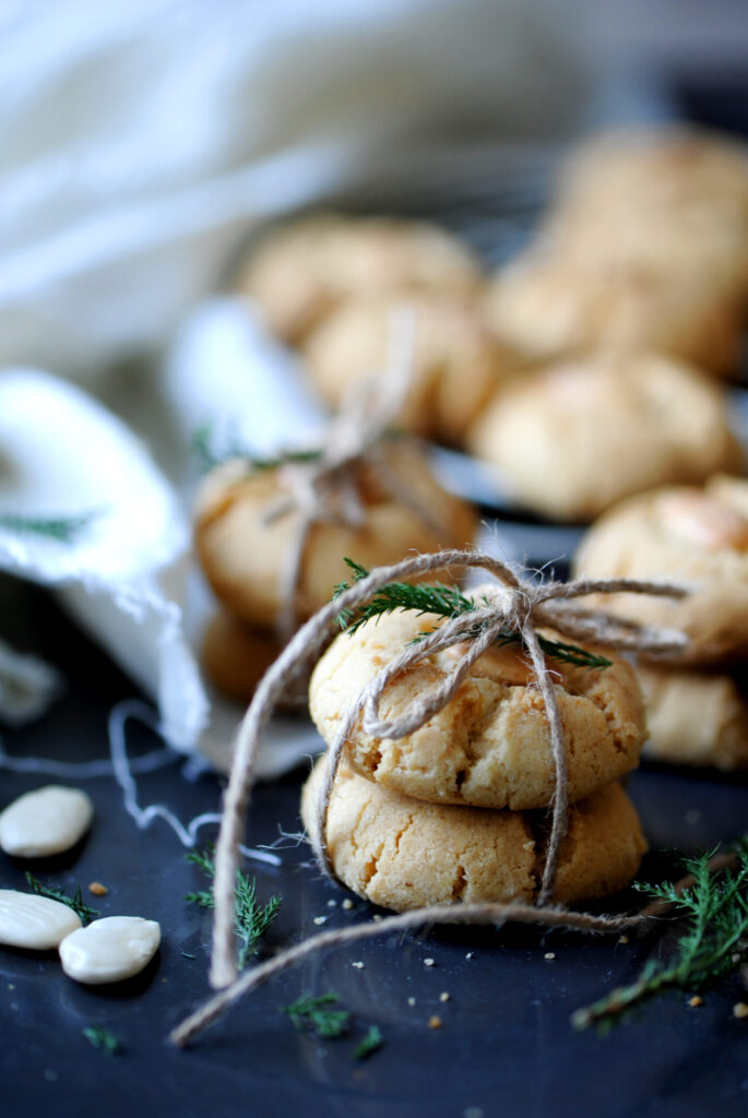 Close-up of two stacked tahini cookies tied with twine on a dark surface.