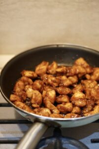 Baked chicken bites coated in a glossy reddish-brown sauce in a skillet.
